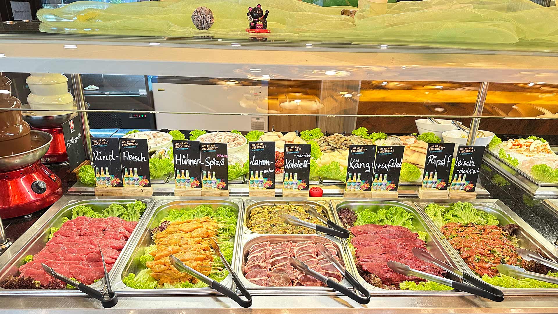 Eine Auswahl an Fleischbuffet mit Beschilderung und Rind, Huhn, Lamm, Känguru auf grünem Salat.